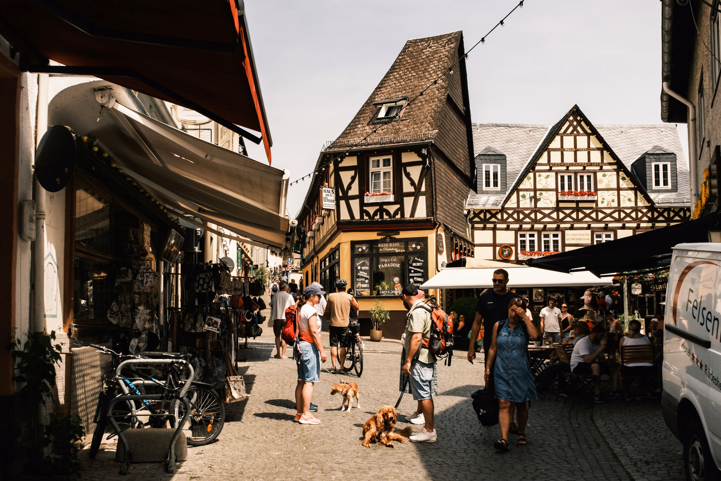 Besucher schlendern durch eine Altstadtgasse mit Fachwerkhäusern, Cafés und Läden