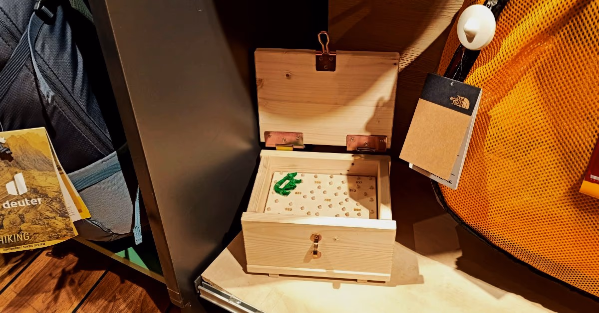 Geöffnete Holzkiste zwischen Rucksäcken und Ausrüstung in einem Outdoor-Laden