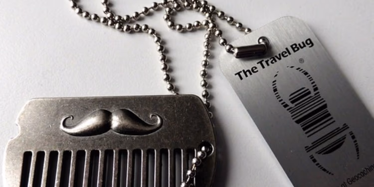 Metallanhänger „The Travel Bug“ und ein Kamm mit Schnurrbart-Motiv an einer Kugelkette