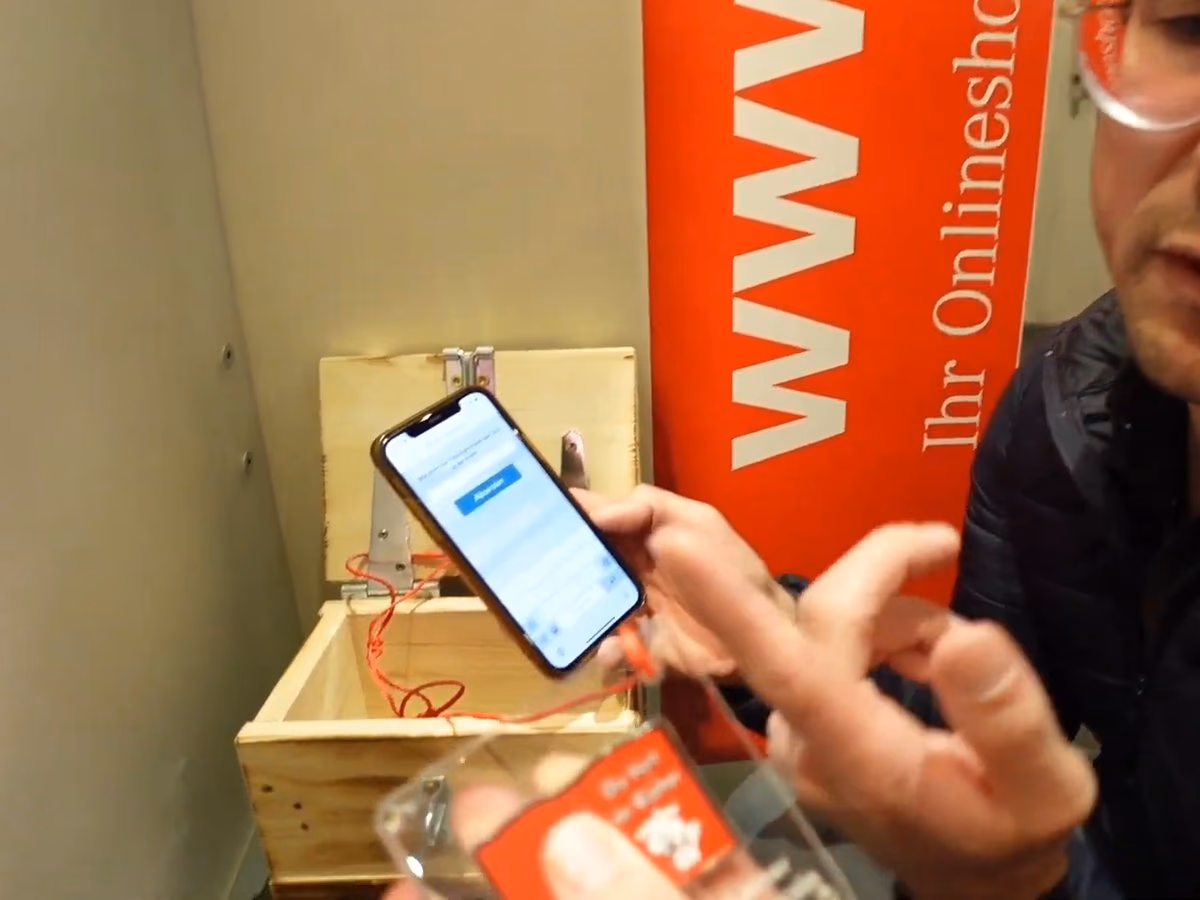 Daniel Pflieger an der geöffneten Holzkiste in einer Hugendubel-Filiale, das Smartphone mit der App in der Hand