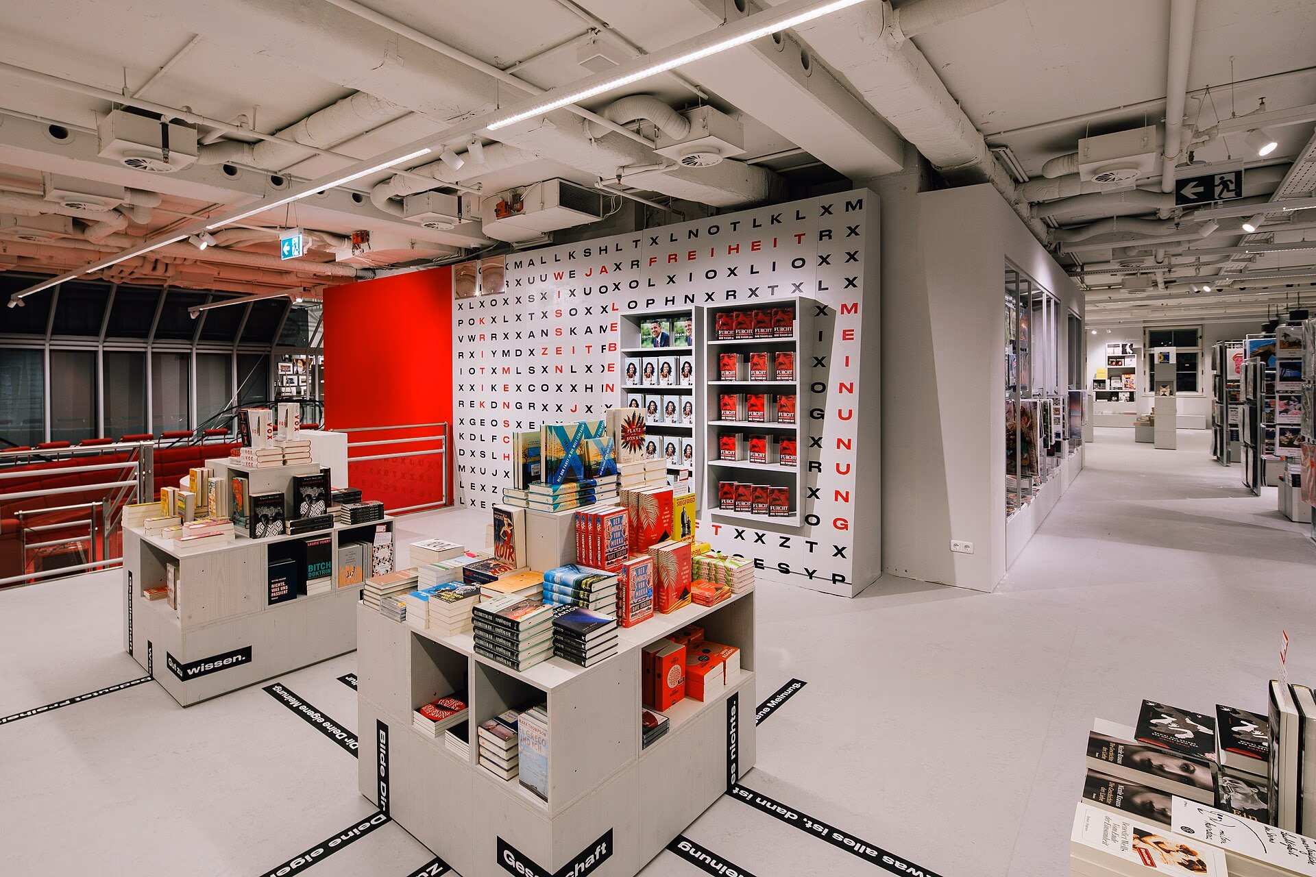 Verkaufsfläche einer Hugendubel-Buchhandlung mit Büchertischen, Regalen und einer Wand aus Buchstaben