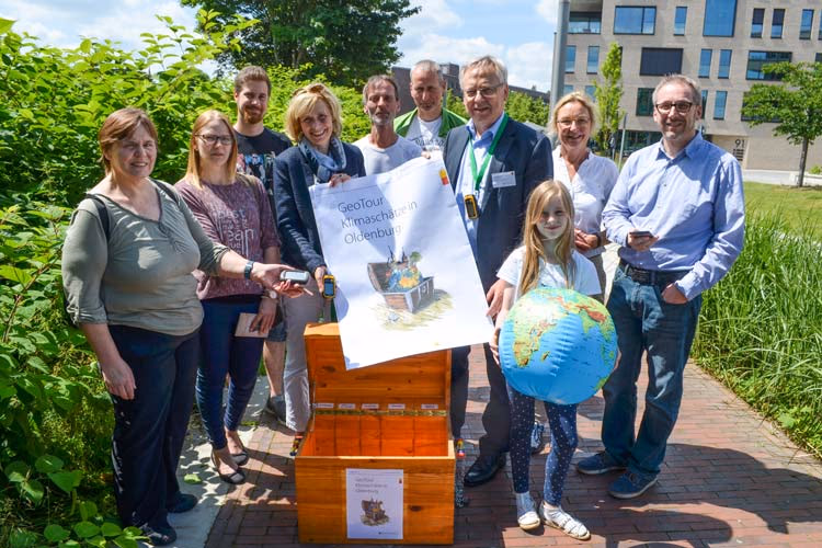 Start der GeoTour „Klimaschätze in Oldenburg“: Eine Gruppe mit Plakat und geöffneter Schatzkiste, vorn ein Mädchen mit aufblasbarem Globus