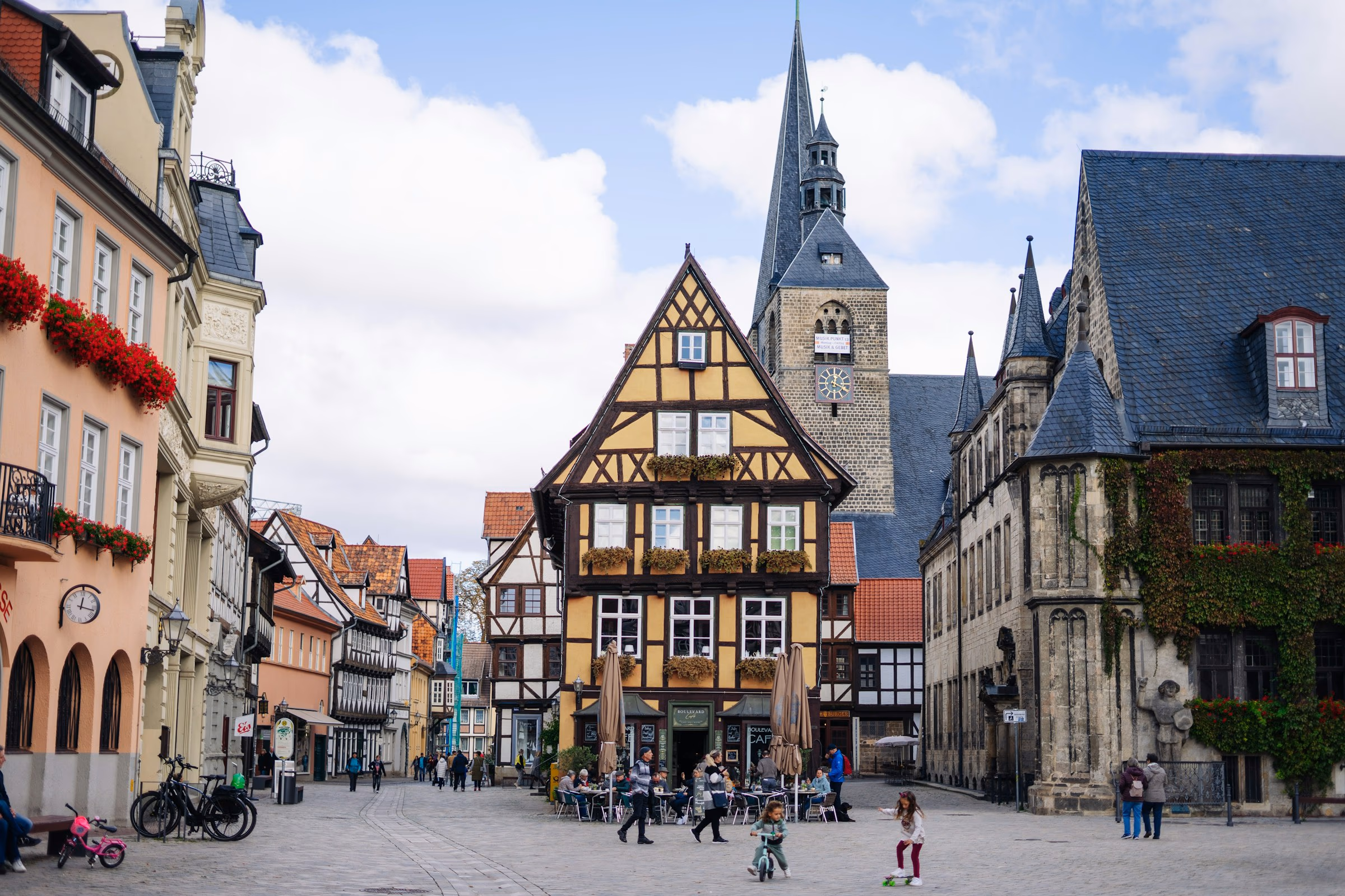 Marktplatz von Quedlinburg mit gelbem Fachwerkhaus, gotischem Rathaus und Straßencafé